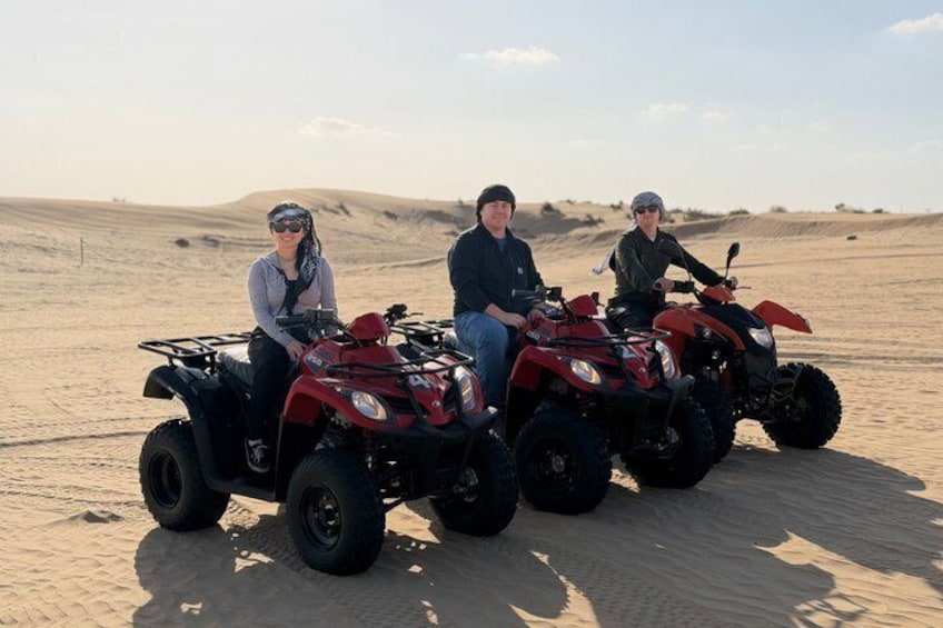 Three people on ATVs in a desert landscape. 5