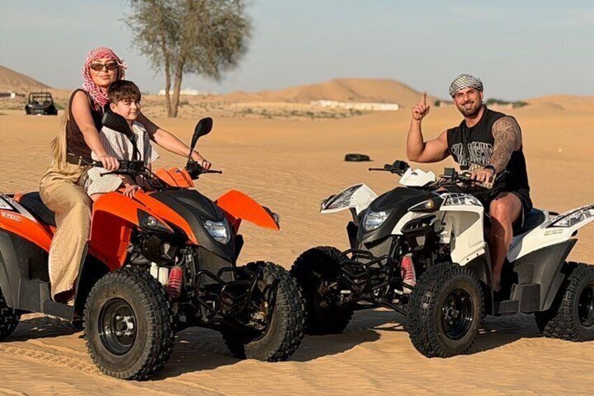 Two people on ATVs in a desert landscape with sand dunes and sparse vegetation. 3