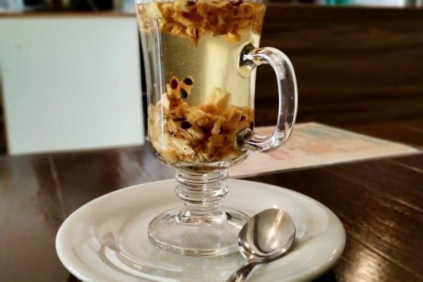 En dessert i et glas med hank, serveret på en hvid tallerken med en ske. 4