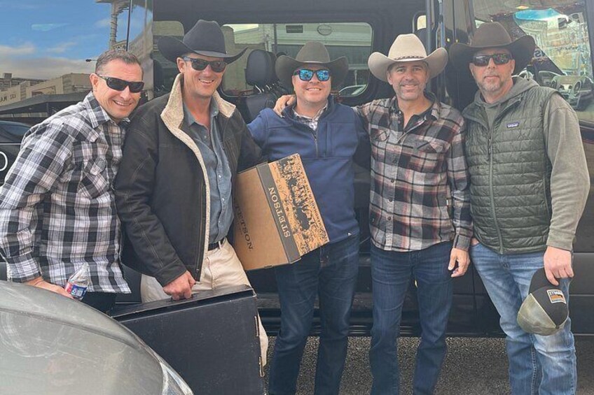 A group of people standing in front of a vehicle, some holding boxes. 2