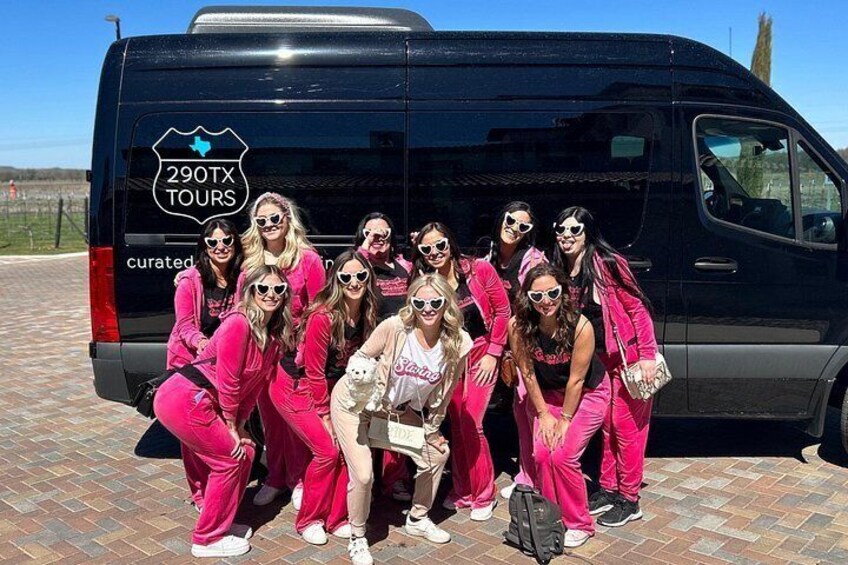 A group of people posing in front of a black van with '290TX TOURS' written on it. 4