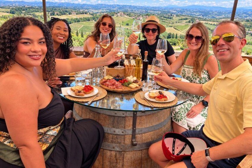 A group of people toasting at a table with wine glasses, surrounded by a scenic landscape. 3