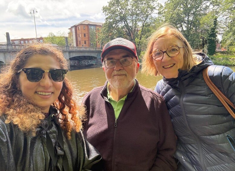 Three people standing in front of a bridge with a building in the background. 4