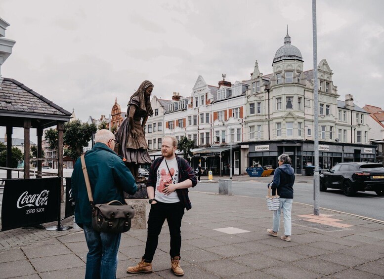 A street scene with a statue, historic buildings, and a Coca-Cola sign. 1
