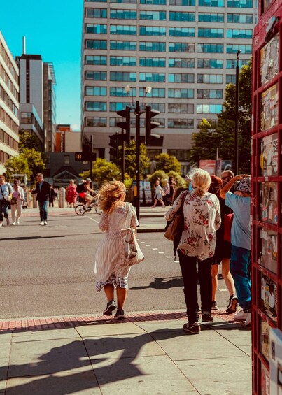 A busy urban street with pedestrians, a red telephone booth, and modern buildings. 5