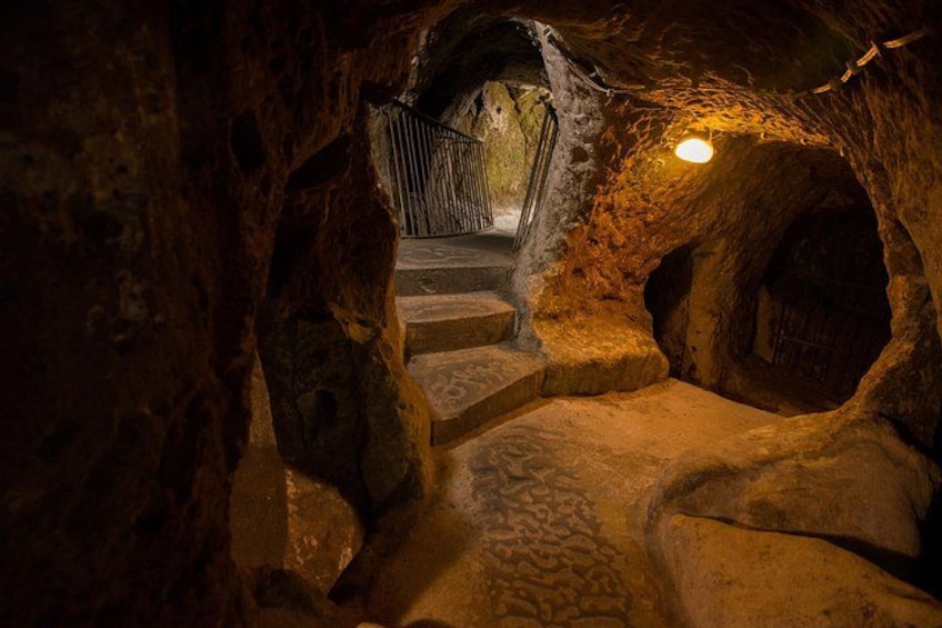 A stone staircase in a cave with a metal gate at the top. 3