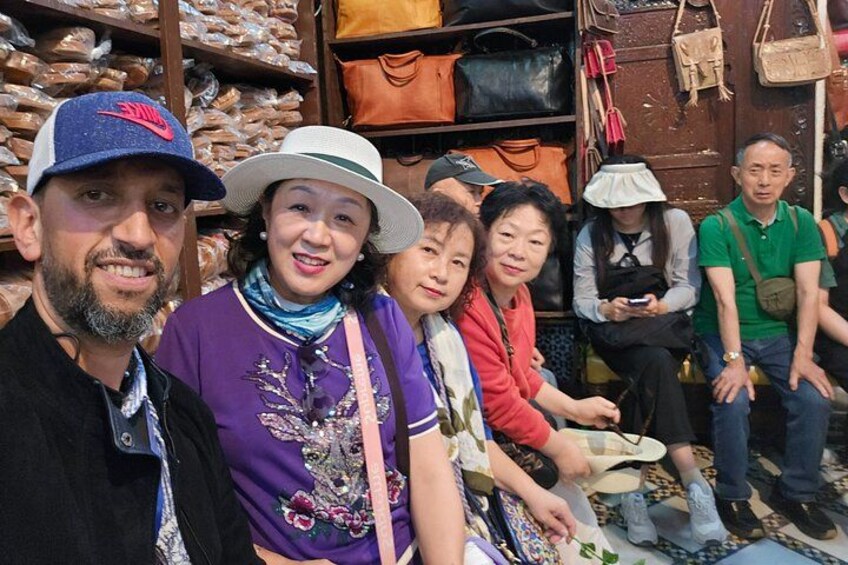 A group of people in a market with bags and shoes on display. 2