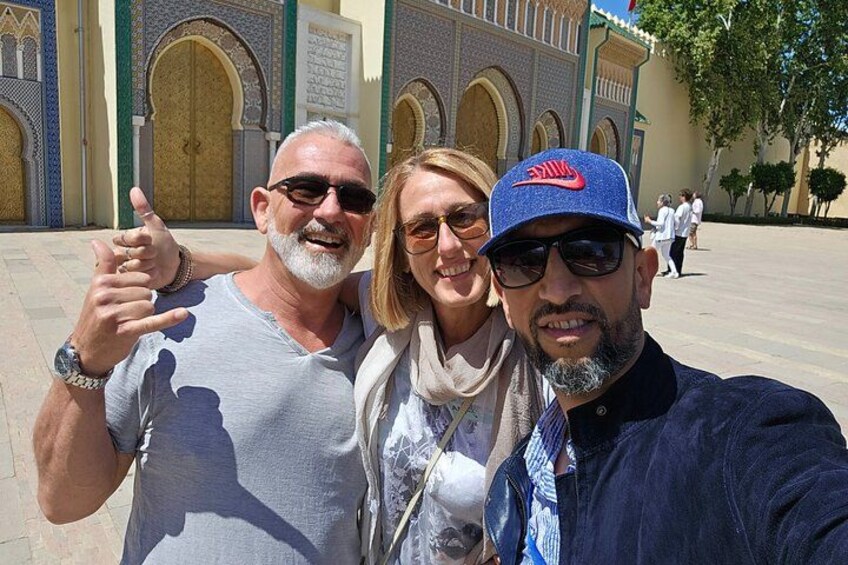 Three people taking a selfie in front of a building with arches and a large door. 1
