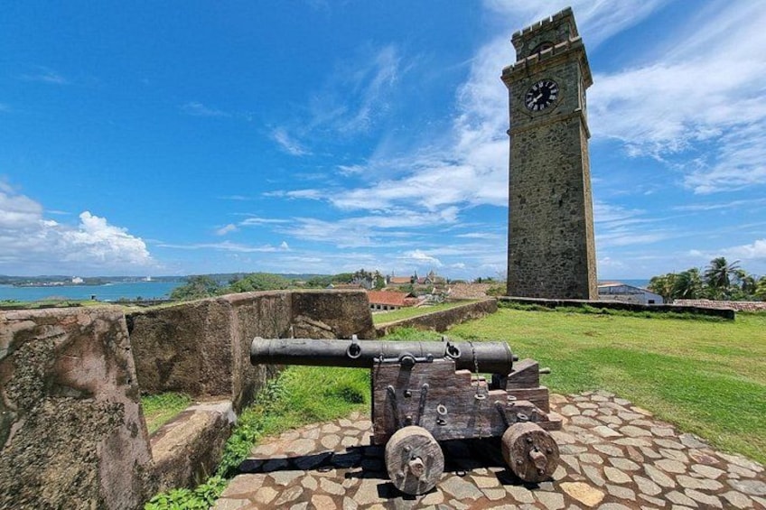 Un canon, une tour d’horloge en pierre et un paysage côtier. 4