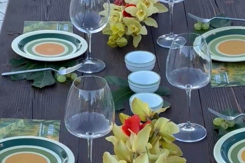 A wooden table set for a meal with plates, bowls, and wine glasses. 2