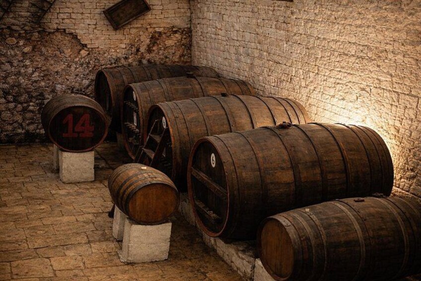 Wooden barrels stacked against a brick wall in a cellar. 4