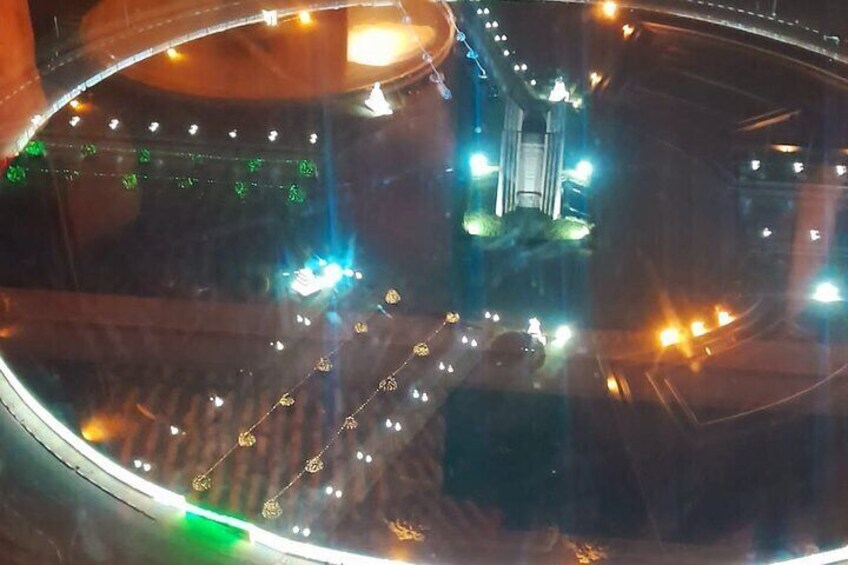 A nighttime view of a roundabout with multiple lanes of traffic, illuminated by streetlights. 3