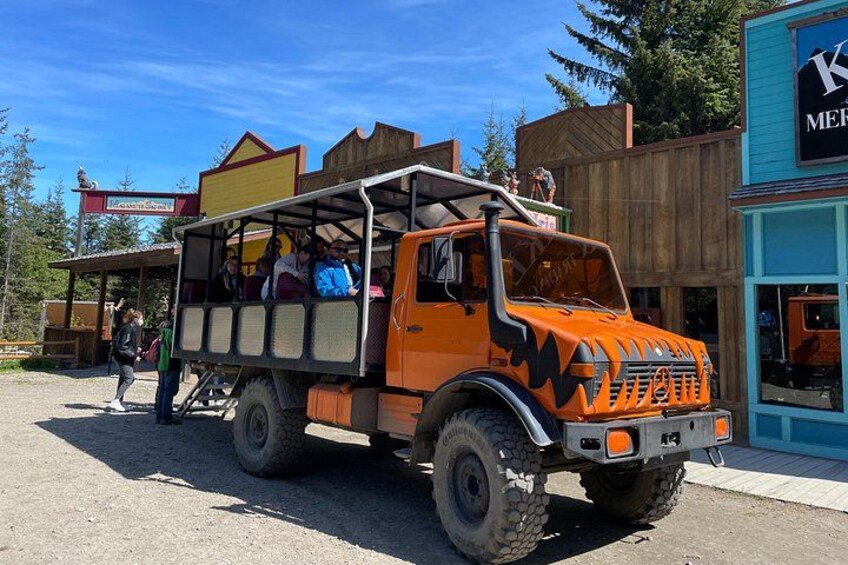 Un camion arancione con passeggeri parcheggiato di fronte a un edificio con un'insegna. 3