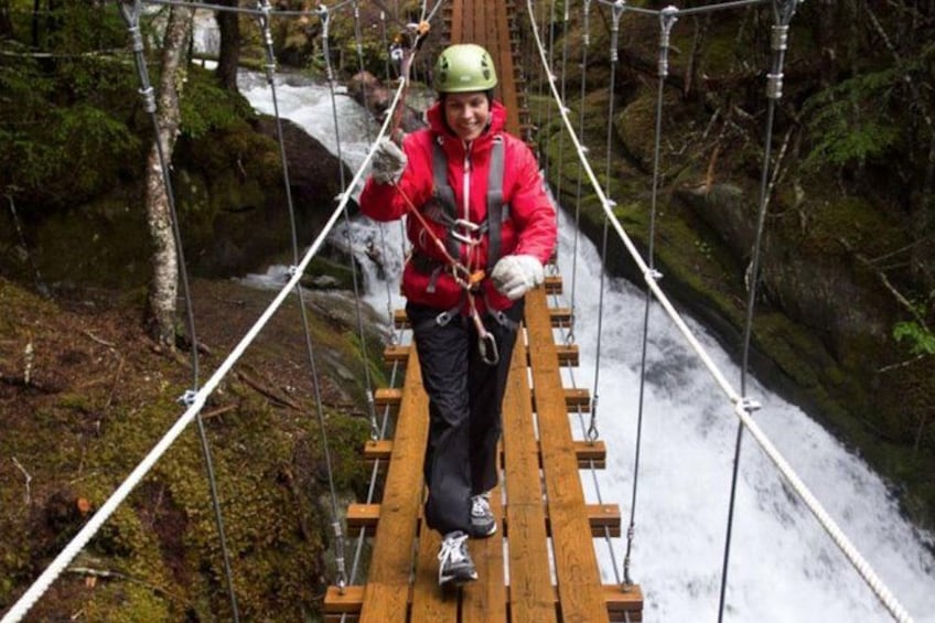 Una persona su un ponte sospeso sopra un fiume in una zona boscosa. 5