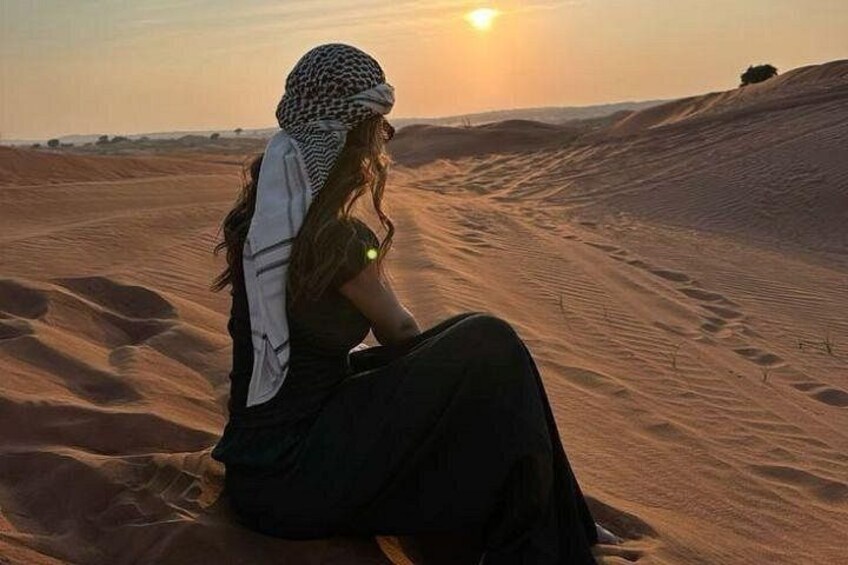 Une personne assise sur une dune de sable au coucher du soleil. 5