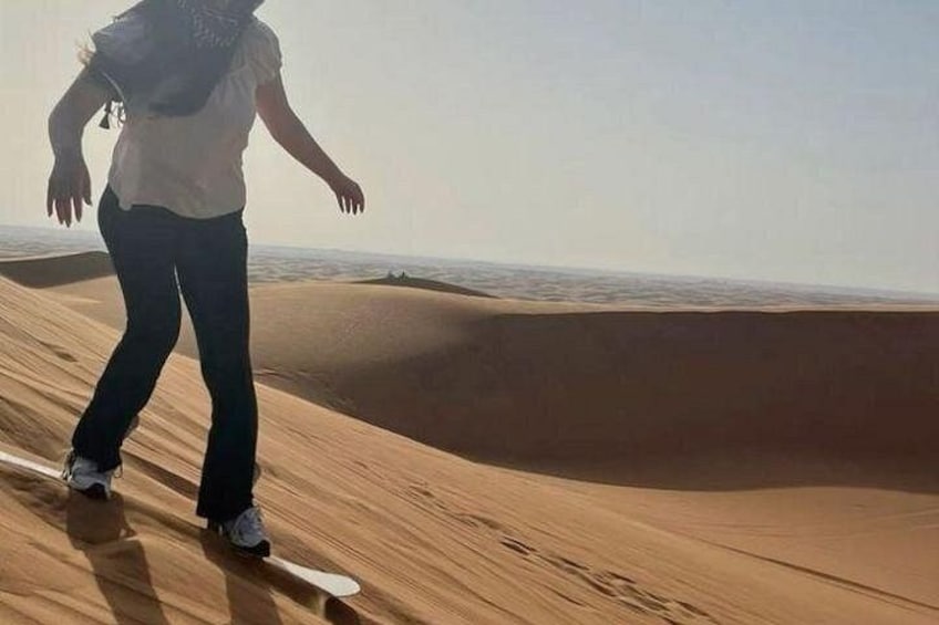 Une personne dévalant une dune de sable sur une planche à neige. 3