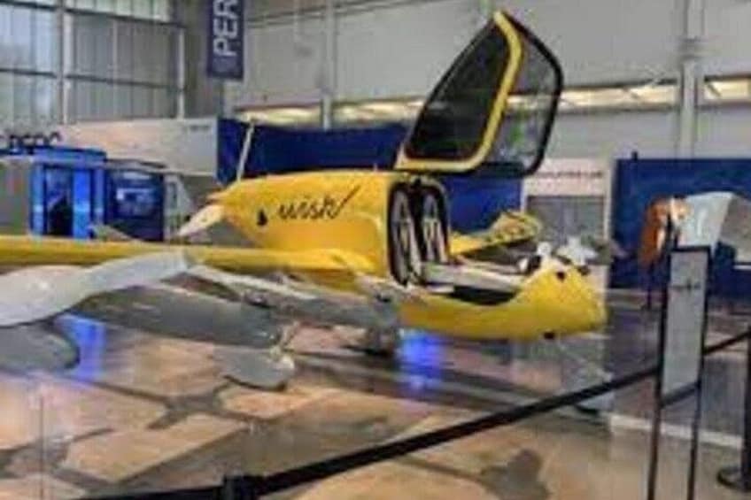 Een gele auto met openstaande deuren, tentoongesteld in een showroom. 2