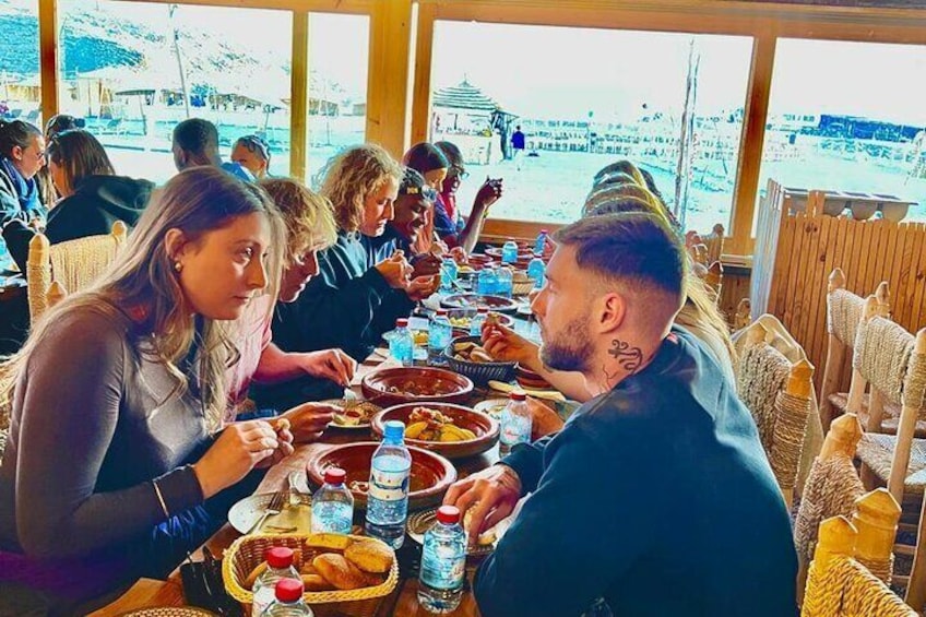 A group of people dining at a table with various dishes and drinks. 1