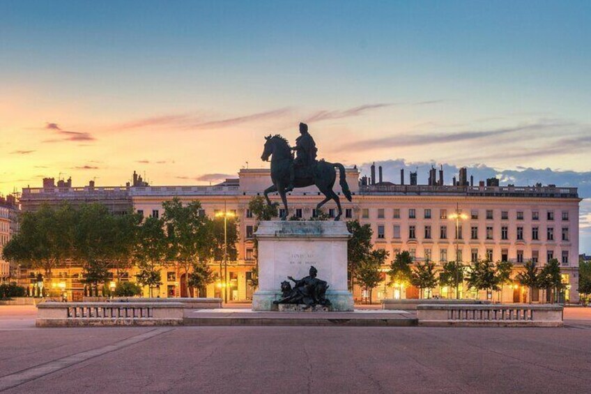 Una estatua de un hombre a caballo en una plaza, con edificios al fondo. 1