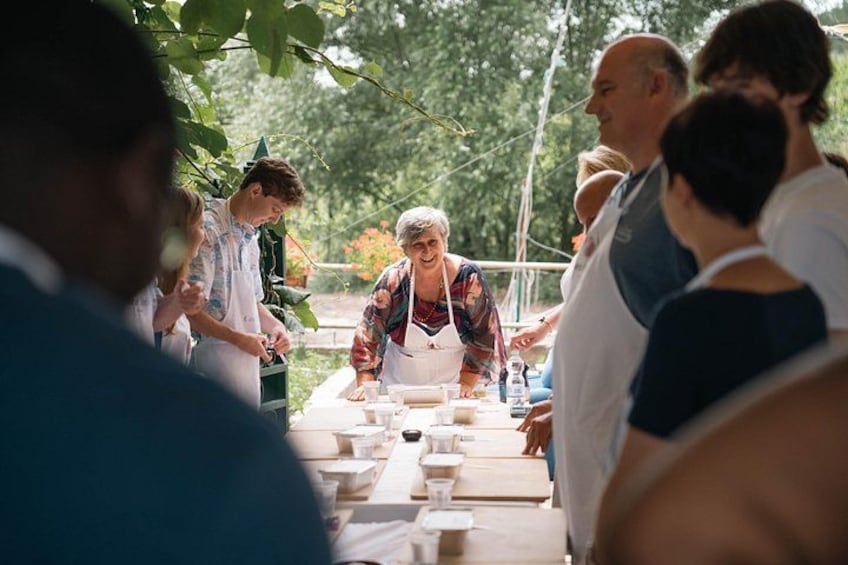 Een groep mensen verzameld rond een tafel buiten, vermoedelijk bezig met koken of voedsel bereiden. 5