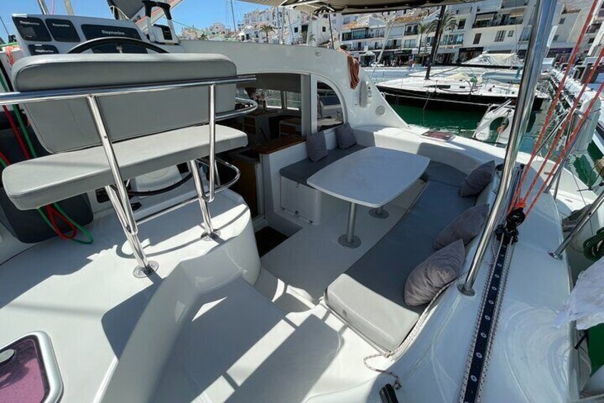 A boat deck with seating, a table, and a steering wheel. 5