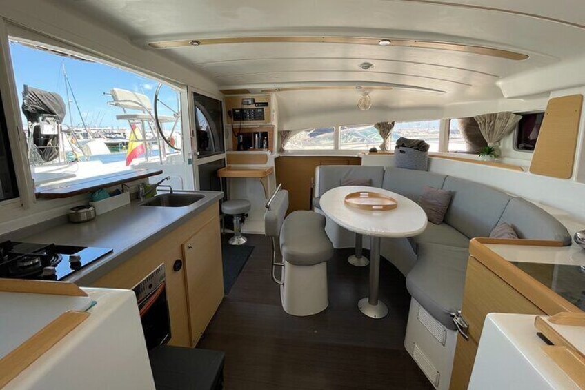 A compact galley with a stove, sink, and seating area. 3