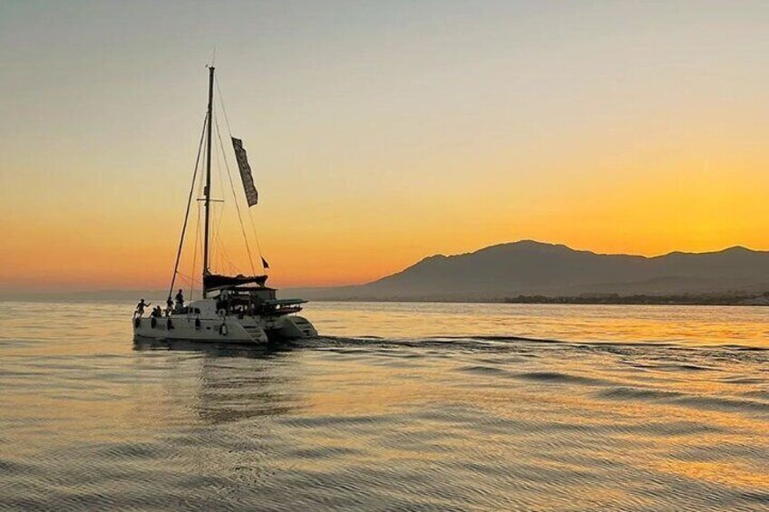 A sailboat on calm waters during sunset with mountains in the background. 2