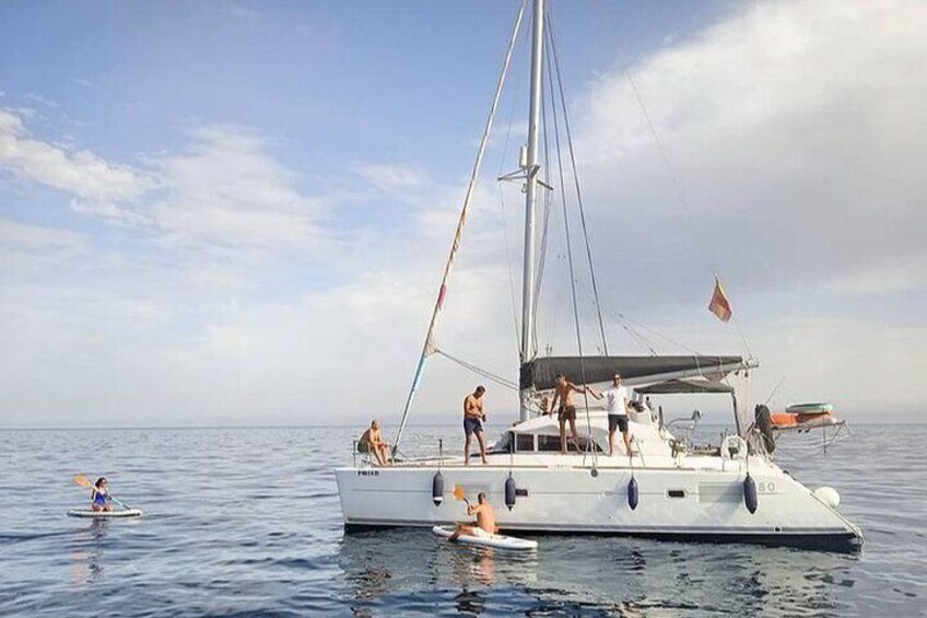 A sailboat with people on deck and a person paddling nearby. 4