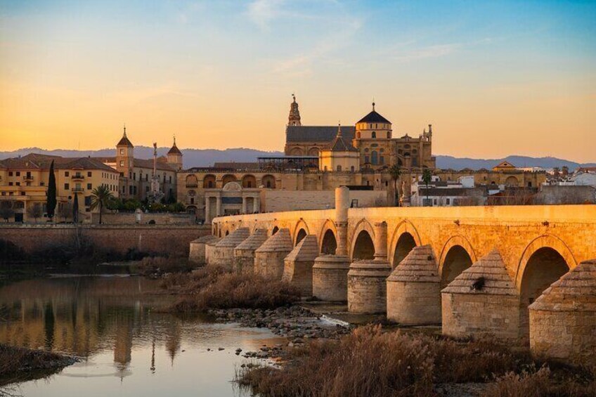 A historic bridge with multiple arches, a river below, and a prominent building with a dome in the background. 3