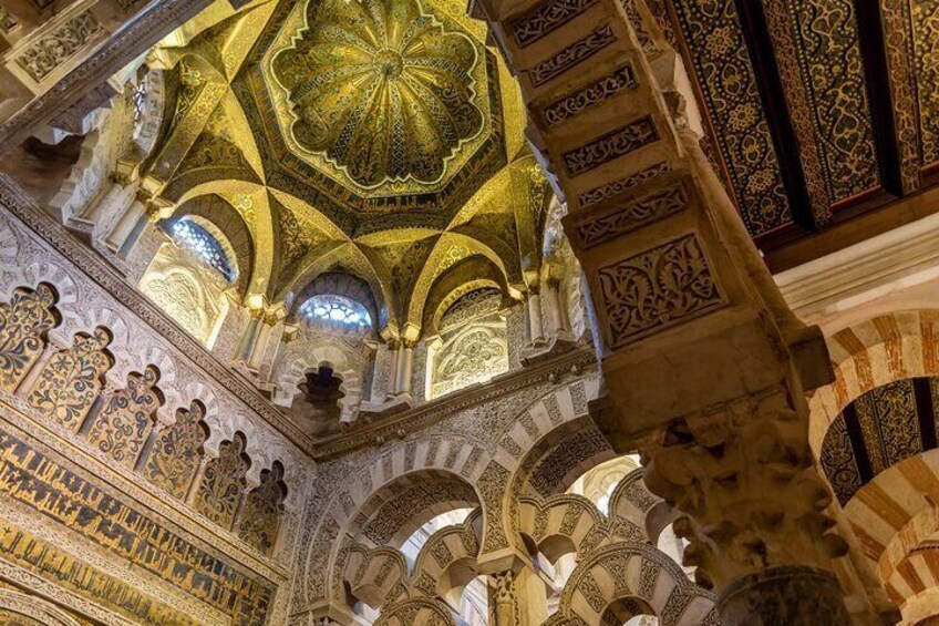 An ornate interior with a large, intricately designed dome ceiling and detailed wall carvings. 4