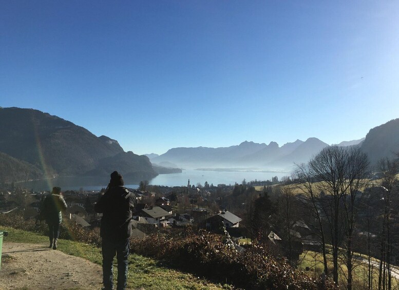 Una persona de pie en una colina con vistas a un lago y montañas al fondo. 2