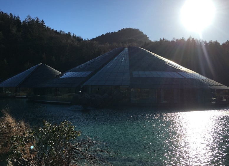 Una hilera de edificios con techo de cristal junto a un lago, con la luz del sol reflejándose en el agua. 4