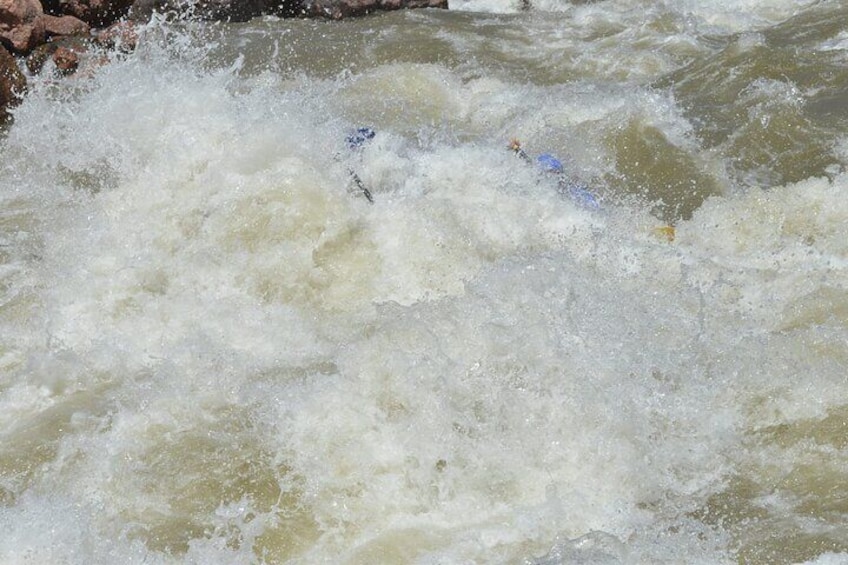 Scena di rafting in acque vive, con acqua impetuosa e una persona in kayak blu. 2
