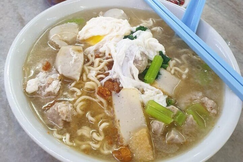 Un bol de soupe de nouilles contenant divers ingrédients, comme du tofu, des légumes et de la viande. 1