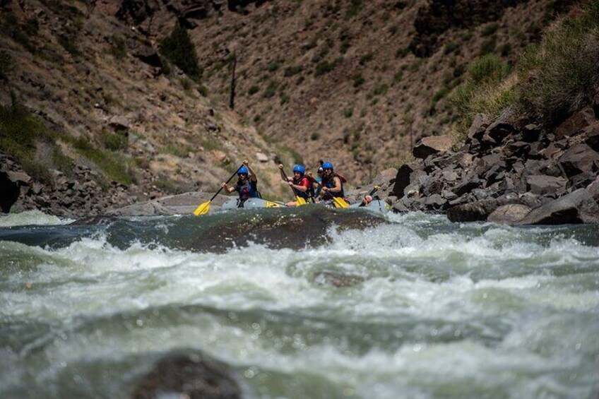 A group of people kayaking on a river surrounded by rocky terrain. 5
