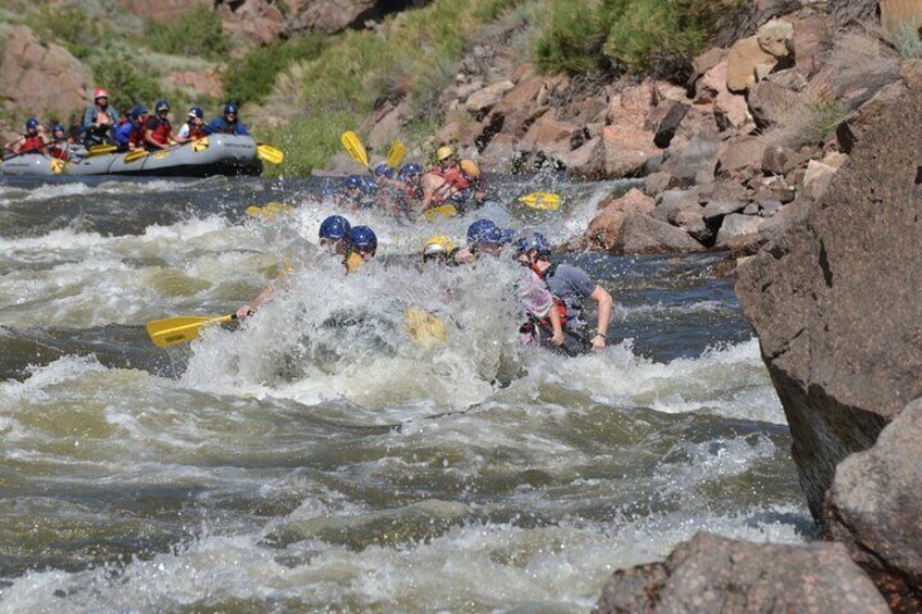 A group of people rafting down a river with rapids. 1