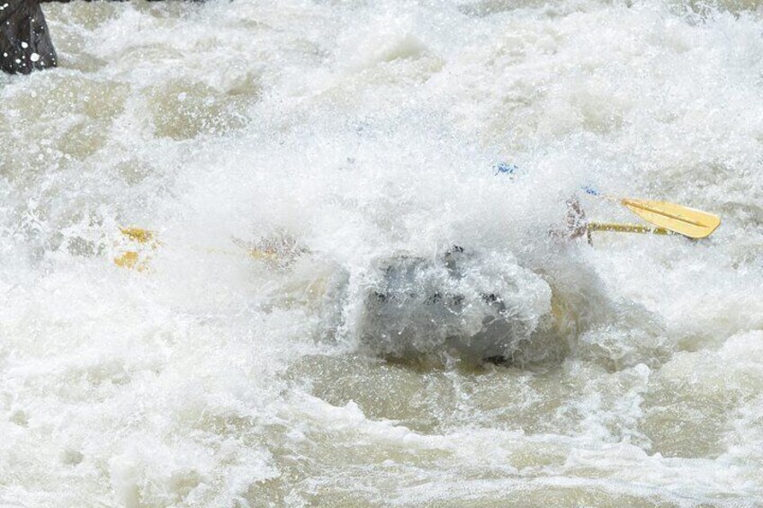 A person navigating a white water raft through turbulent rapids. 3