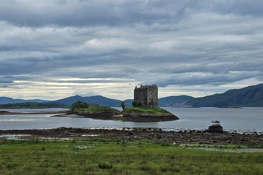 A castle on a small island surrounded by water, with a cloudy sky above. 2