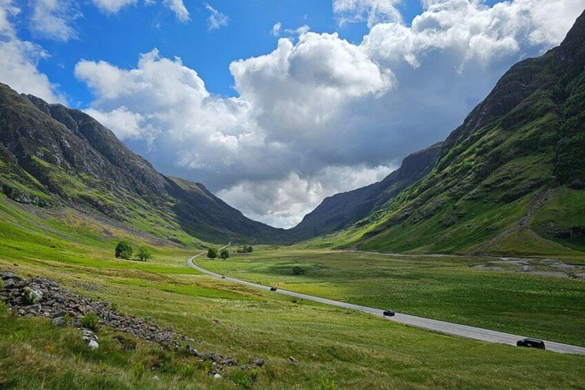 A winding road through a valley with mountains on either side. 4