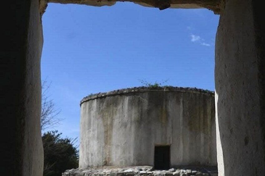 A concrete structure with a circular top and a small door at the base, surrounded by a clear blue sky. 4