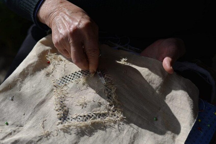 A hand sewing a piece of fabric with a needle and thread. 5