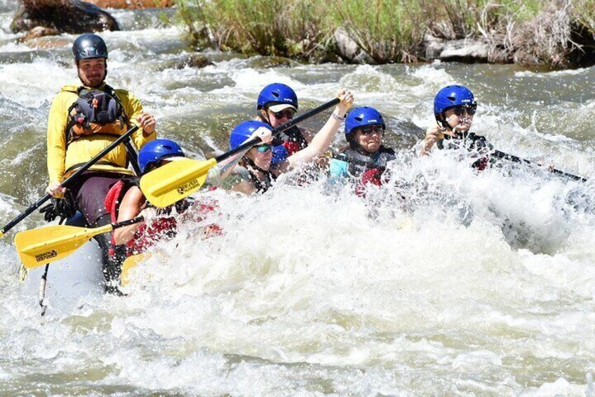 A group of people in a yellow kayak navigating a river with white water rapids. 3