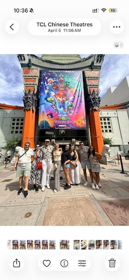 A group of people posing in front of a theater with a large Mario movie poster. 3