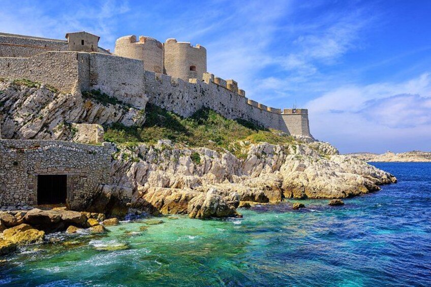 Una fortezza costiera con un mare blu cristallino, scogliere rocciose e un ingresso in pietra. 2
