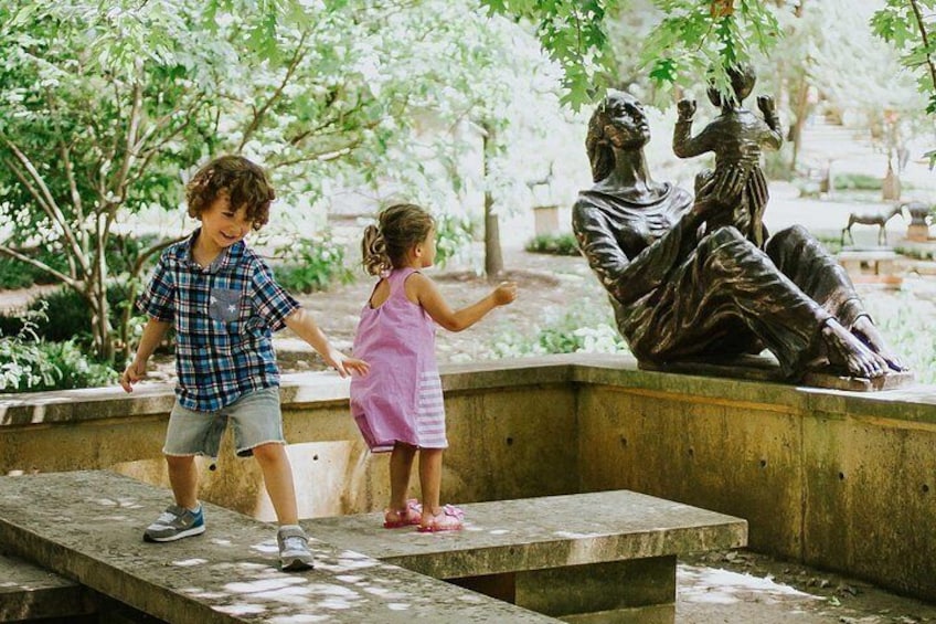 Children playing near a sculpture in a park. 5