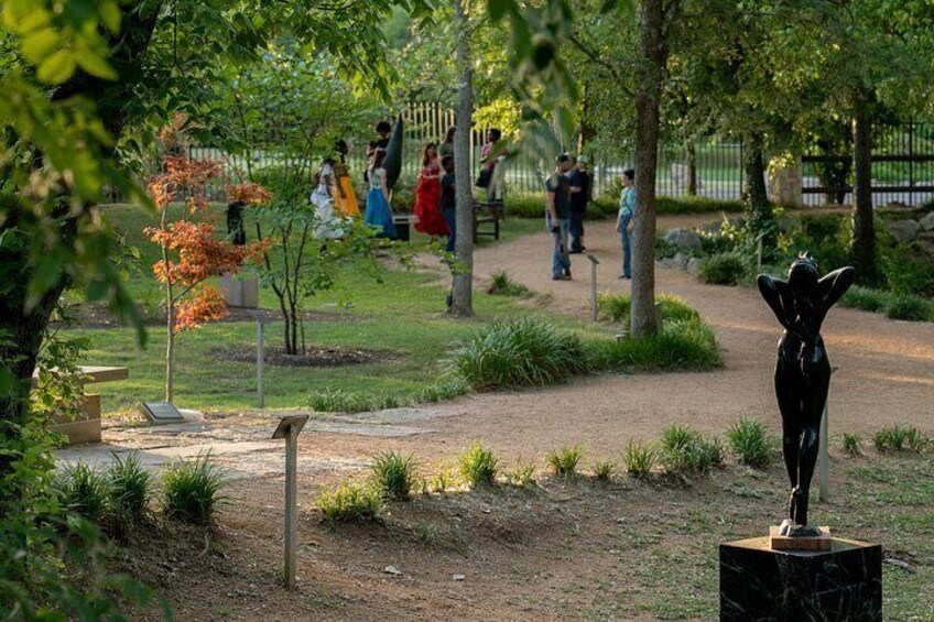 A park with a sculpture, walking paths, and people. 4