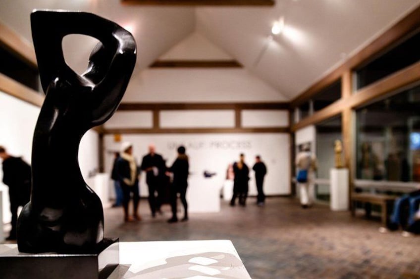 A modern interior space with a sculpture, a group of people, and a sign with text. 2