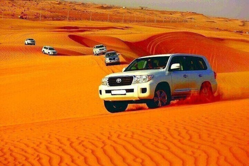 A white SUV driving through a desert with sand dunes. 4