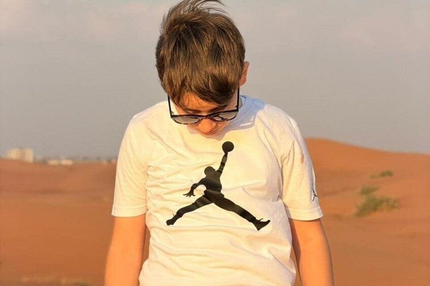 En person iført en hvid t-shirt med et sort silhouet af en person, der springer. 5