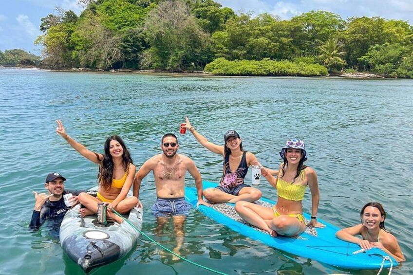 A group of people on a boat in a tropical setting with clear water and lush greenery in the background. 5